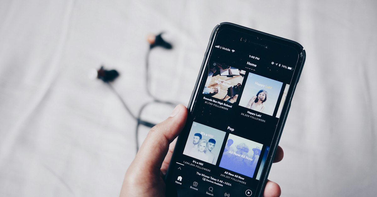 Smartphone affichant une application de streaming musical, avec des écouteurs