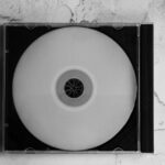 CD vierge dans un boîtier cristal posé sur un fond marbré